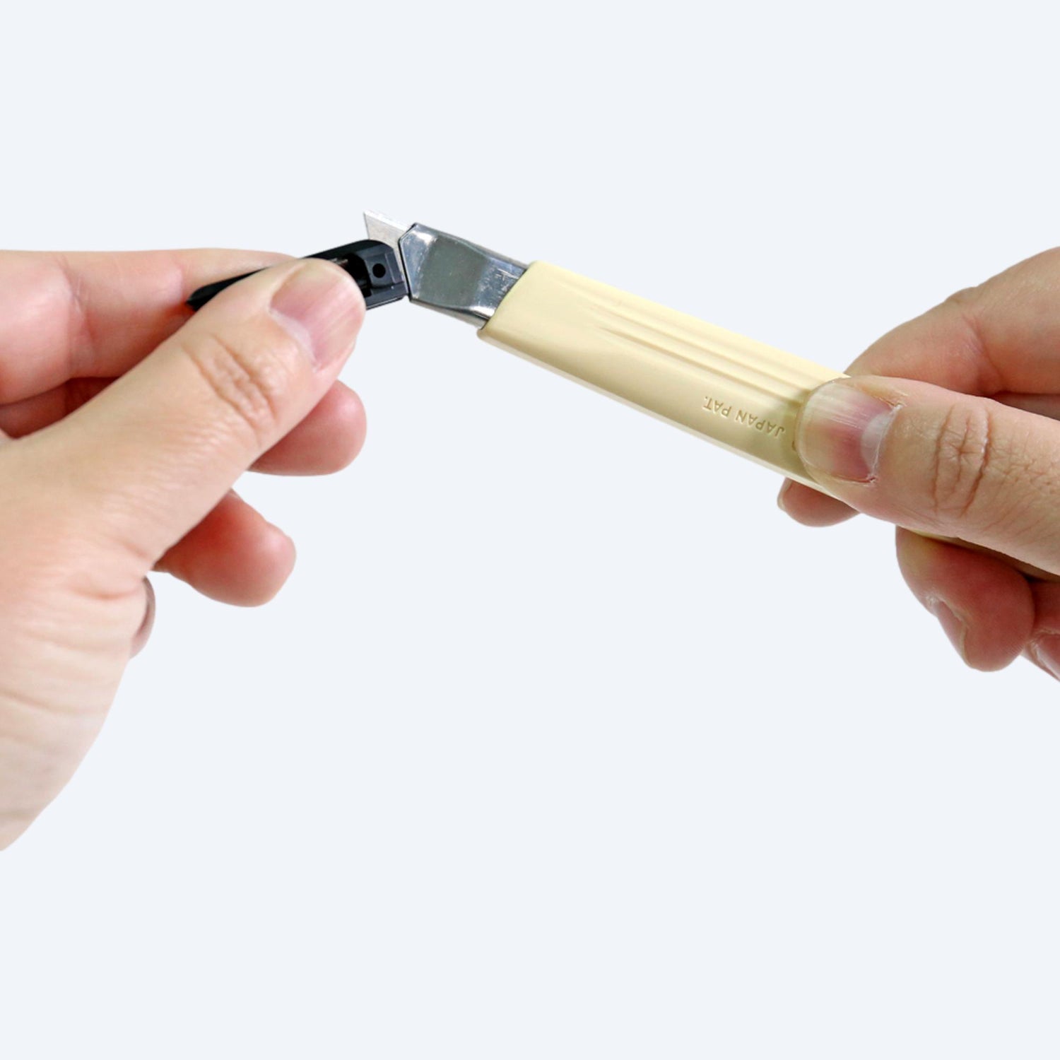手持A-300 NT Cutter 鎅刀,黃色手柄,理想物流剪刀用於包裝,適合批發購買,背景是模糊手指