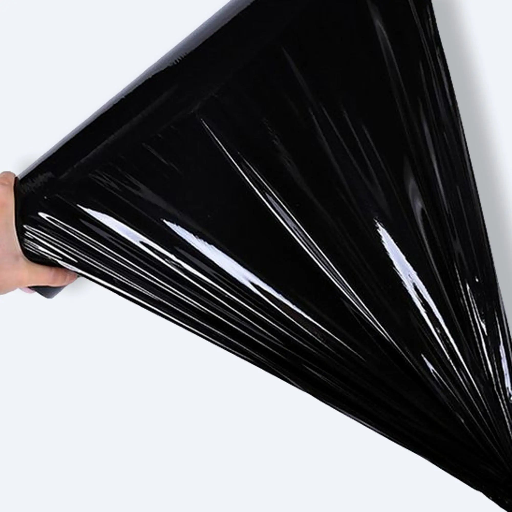 Hand stretching glossy black pallet wrap film to demonstrate elasticity
