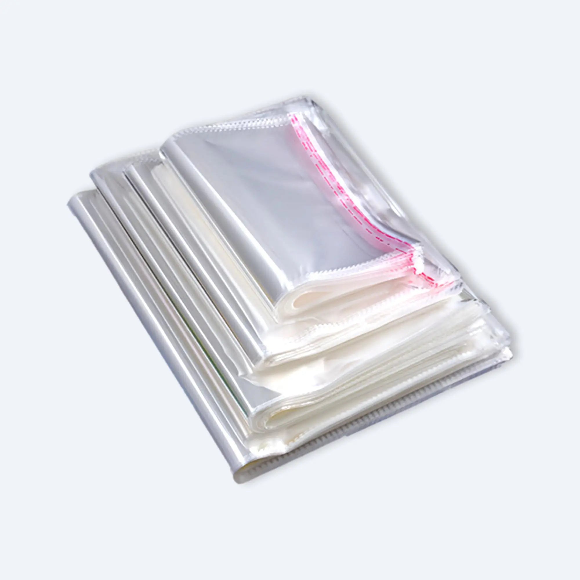 Neatly folded stack of clear OPP self‑adhesive bags showing glossy finish and red tamper‑evident peel strip.