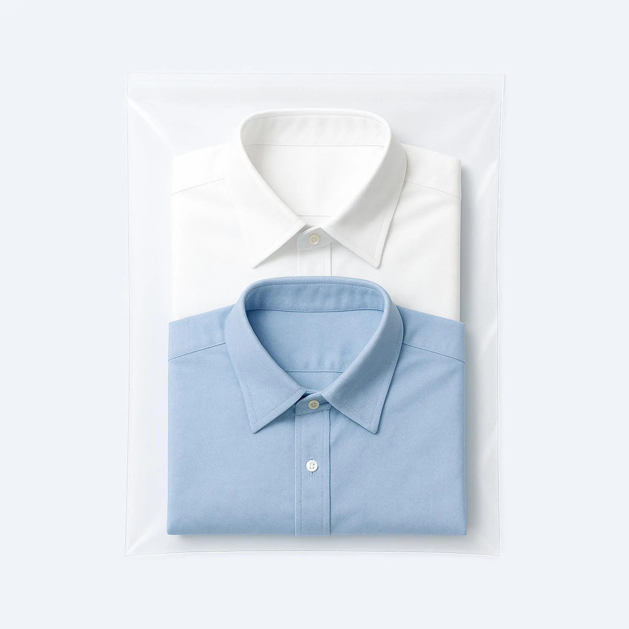 Two folded dress shirts, white and blue, neatly packed in a transparent PE flat bag for retail presentation.