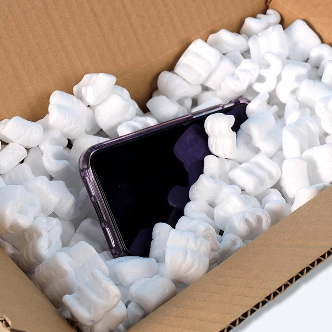 精細的發泡膠粒填充物環抱著一部手機，置於紙質運輸箱內，展現香港包裝供應商對電子產品保護的專注與承諾。