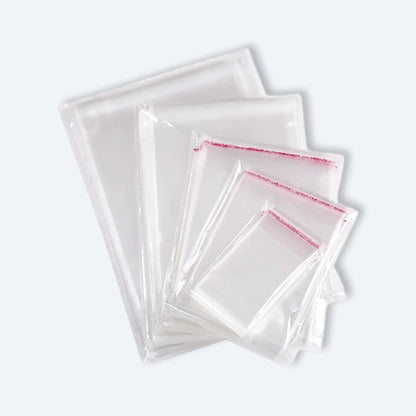 Fan display of clear OPP self‑adhesive bags in mixed sizes, each with red peel‑and‑seal strip for secure packaging.