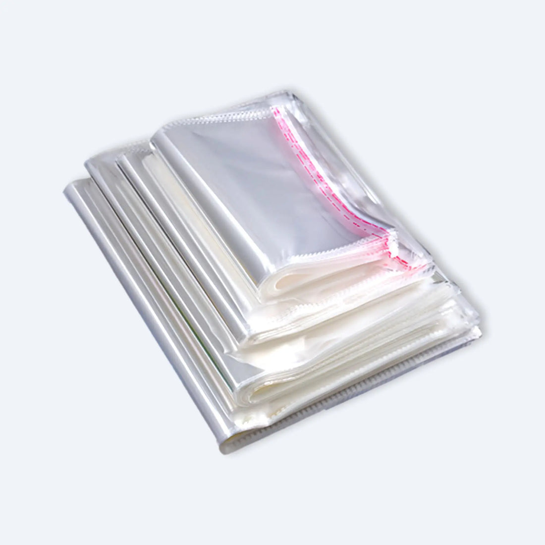 Neatly folded stack of clear OPP self‑adhesive bags showing glossy finish and red tamper‑evident peel strip.