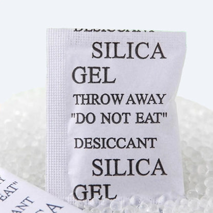Silica‑gel desiccant sachet standing upright among loose beads, illustrating powerful moisture‑absorption capacity.